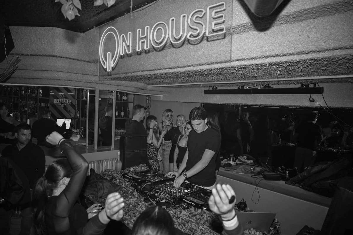 The ONHOUSE neon sign above a packed DJ booth, shot on flash in black and white